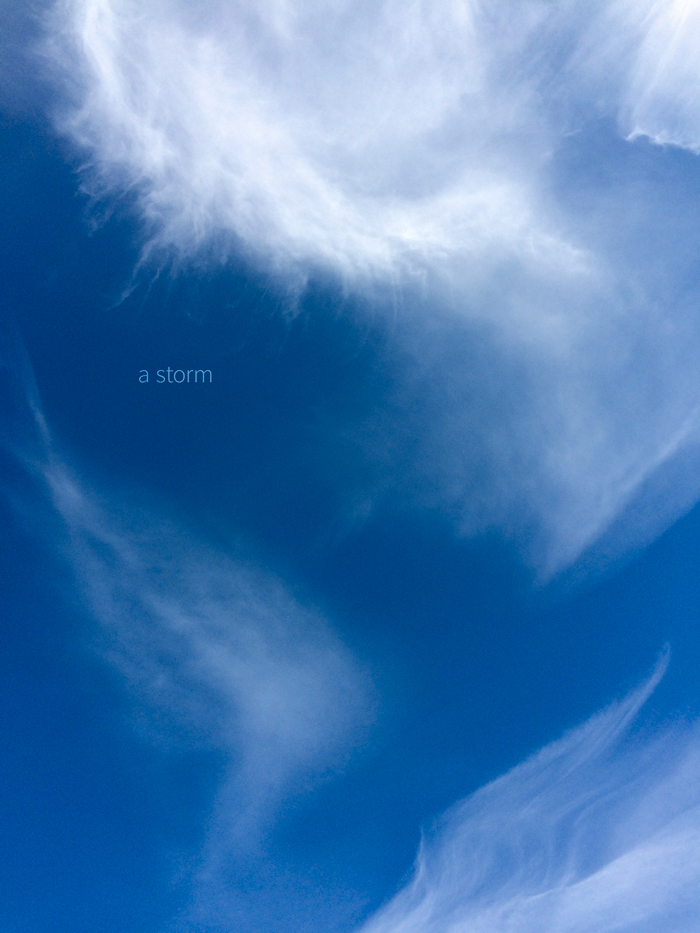 A photograph of more substantial clouds in a blue sky with the words "a storm"